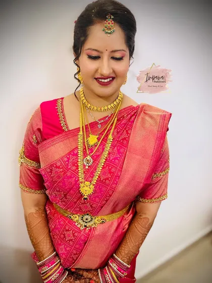 A smiling bride ready for her big day. This look features a classic pink Kanjeevaram saree, complemented by soft glam makeup with a pink lip and defined eyes.