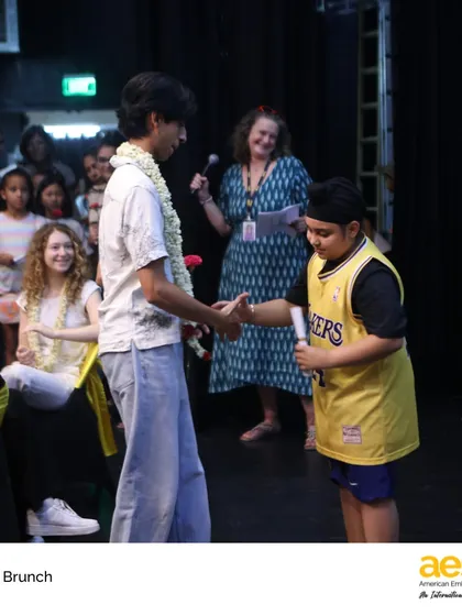A third-grade buddy presents a gift to a senior, a heartwarming tradition that connects our youngest and oldest students. It’s a beautiful example of the cross-divisional community we foster.