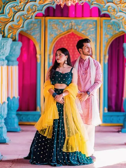 This couple chose a very colorful and grand location for their pre-wedding shoot. Her dark green and yellow lehenga and his pink kurta create a stunning visual contrast.