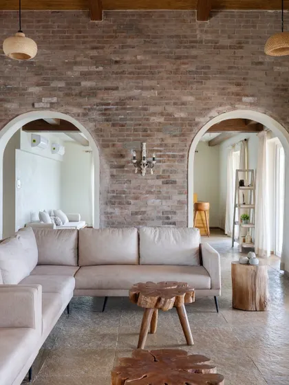 The living room of the 'Ekaant' villa, showing the harmony between the rough texture of the brick wall and the smooth finish of the neutral-toned sofa.