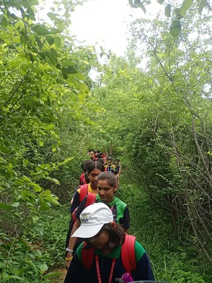 Students from VIBGYOR High walk single-file through a dense, lushly restored trail in the Aravalli Biodiversity Park.