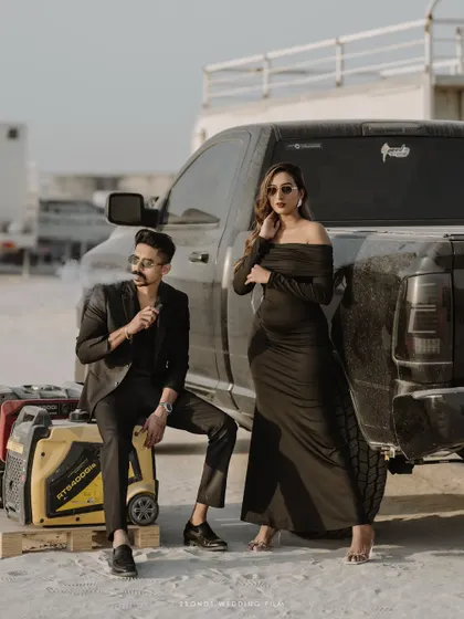 A high-fashion, edgy portrait of the couple posing by a truck in the desert, showcasing a modern and bold pre-wedding photography style.