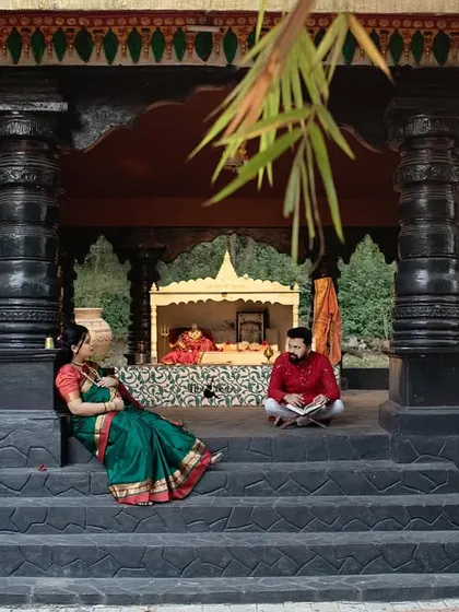 A wide shot showing the couple in a peaceful temple courtyard. This photo captures the serene and spiritual atmosphere of their traditional maternity session.