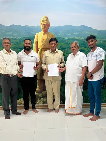 Holding the signed MOU alongside the respected leadership of S-VYASA, including Chancellor Dr. H. R. Nagendra Guruji. We stand before a statue of Swami Vivekananda, whose teachings are our foundation.