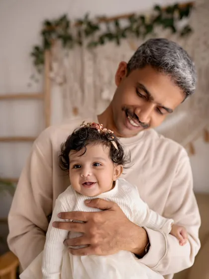 A grandfather smiles down at his baby granddaughter. The love and pride in his eyes are what make this multi-generational photo so special.