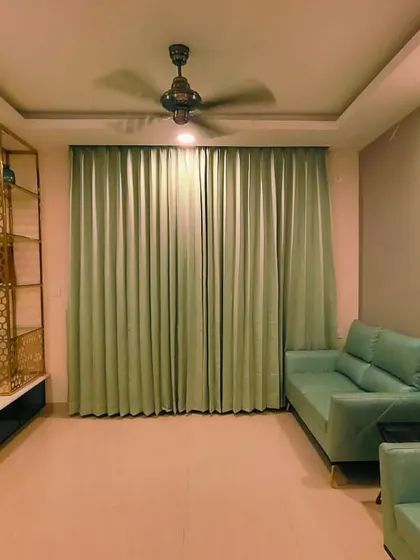 Beautiful, floor-length curtains in a soft sage green, perfectly complementing the matching sofa and adding a touch of serene color to the living room.