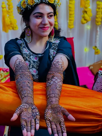 The bride proudly displaying her full bridal henna. The intricate design covers her hands and arms beautifully.