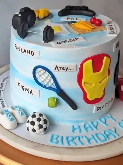 This cake was designed for a colleague's birthday, covered in all his favorite things. This view shows his love for tennis, Figma, and inside jokes like "Gossip" and "Arey."