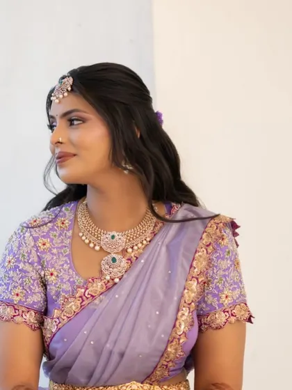 A portrait of the bride in her custom lilac Langa Dhavani. The intricate embroidery on the blouse complements the delicate floral pattern of the skirt.