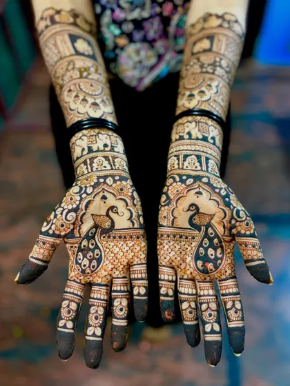 A straight-on view of the peacock bridal mehendi. The dark, rich paste promises a stunning stain for the wedding day.