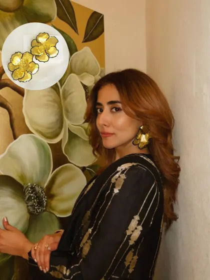 A close-up of Jonita Gandhi wearing the Metallic Black Floral Statement Earrings, with an inset showing the intricate detail of the piece.