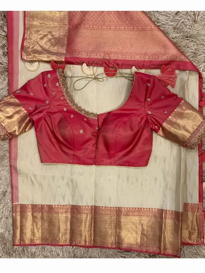 The red blouse paired with a classic off-white and red silk saree, a timeless combination for any bride.