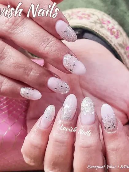 A soft and elegant look with a light pink base and a scattered fade of chunky silver glitter on almond-shaped nails.