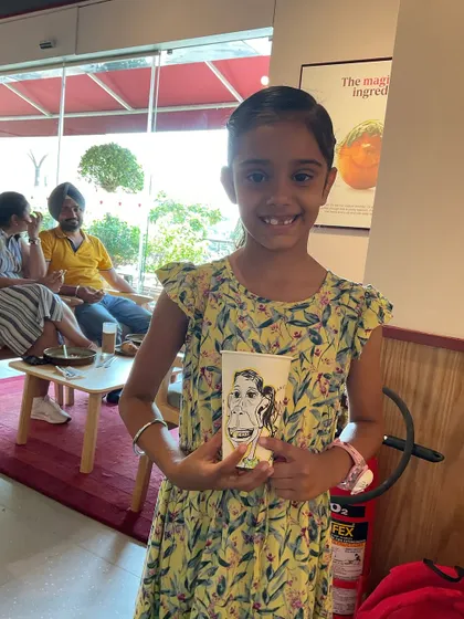 A little girl proudly holding her Pret coffee cup with her own face drawn on it.