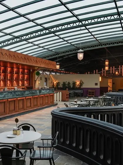 A similar view to the previous image, emphasizing the warm lighting and the rich wood tones of the bar. Every element was chosen to contribute to the narrative of old Calcutta's charm.