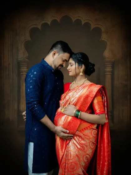 An intimate couple's portrait from a traditional maternity session. The focus is on their connection, with both partners embracing the baby bump, set against a classic arched backdrop.