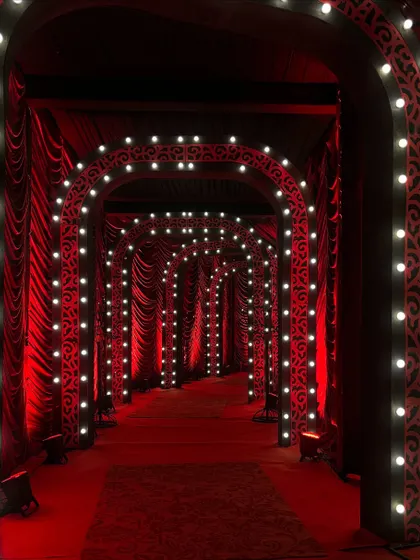 The entrance tunnel for a Las Vegas themed party. I used repeating arches lined with bright bulbs and draped in rich red fabric to create a dramatic and glamorous pathway for guests.