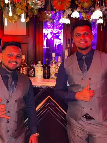 Two of our mixologists ready to deliver double the magic. Dressed in matching vests and ties, they represent the sharp, coordinated look of our team.
