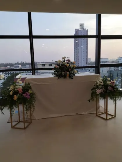 A simple and professional setup for a corporate office event. The floral arrangements are elegant and understated, complementing the modern office space with a city view.