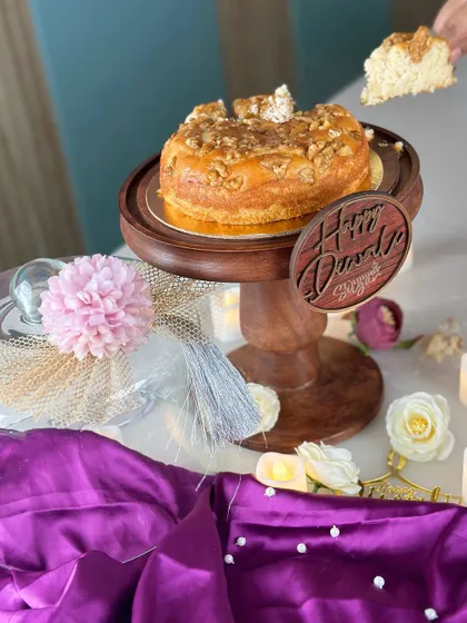 Here, the glass dome is lifted to reveal the walnut tea cake inside the keepsake Diwali hamper, ready to be sliced and enjoyed.