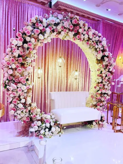 A perfect frame for your special moments. This full-circle floral arch, crafted with thousands of pink and white roses, serves as a stunning photo backdrop or an elegant stage for an engagement or reception.