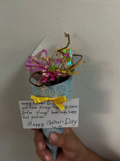 A vibrant pink and yellow bouquet with a touching note. These handmade gifts are a wonderful way for children to express their love and appreciation.