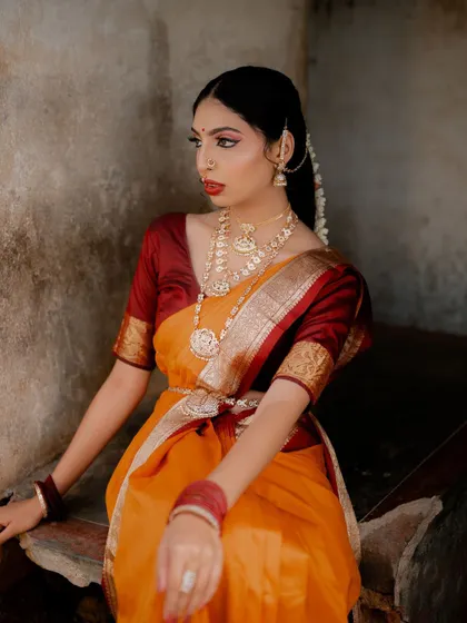 A medium shot showing the bride seated. The composition draws attention to her graceful posture and the beautiful drape of the saree.