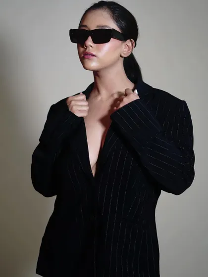 A portrait where the model is adjusting the collar of the blazer. This small action adds a story to the image, making it more engaging than a static pose.