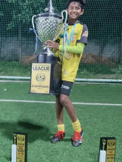 Abhay proudly holding his MVP, Top Scorer, and the U13 Champions trophy from the Mini Dribblers League.