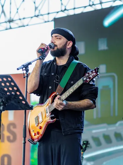 Performing with my guitar at an outdoor concert. I handle vocals and also play guitar, switching between electric and acoustic depending on the song.