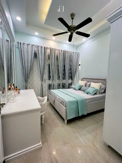 A compact yet stylish bedroom in Haridwar, featuring cool blue and grey tones. The design maximizes space with a sleek bed, a functional dressing unit, and coordinated curtains.