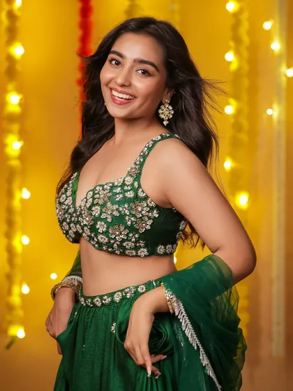 A happy and vibrant shot, capturing a beautiful, genuine smile. The movement in her hair and the bright background lights create a feeling of pure festive joy.