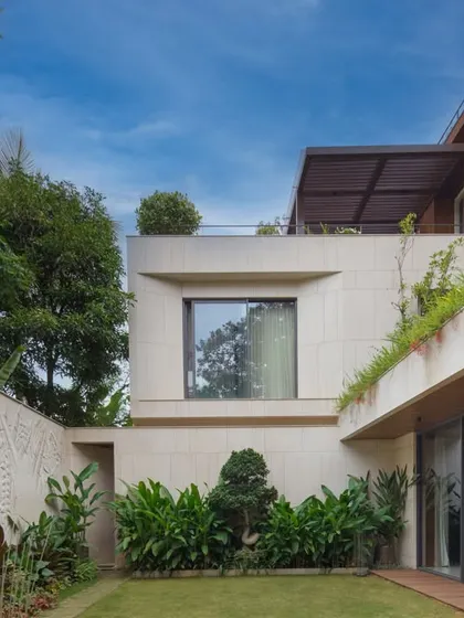 A view of the private lawn and courtyard, framed by a carved marble wall and lush greenery. I design these spaces to be tranquil sanctuaries within the larger property.
