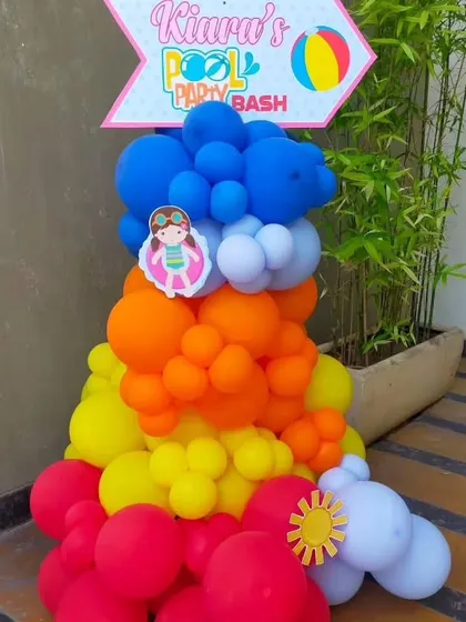 A colorful balloon column with a "Pool Party Bash" sign to welcome guests to the celebration.