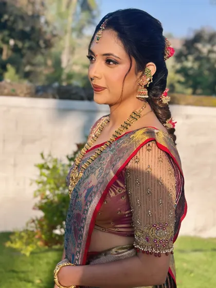 A side profile of Sneha, showing her traditional braided hairstyle adorned with flowers.
