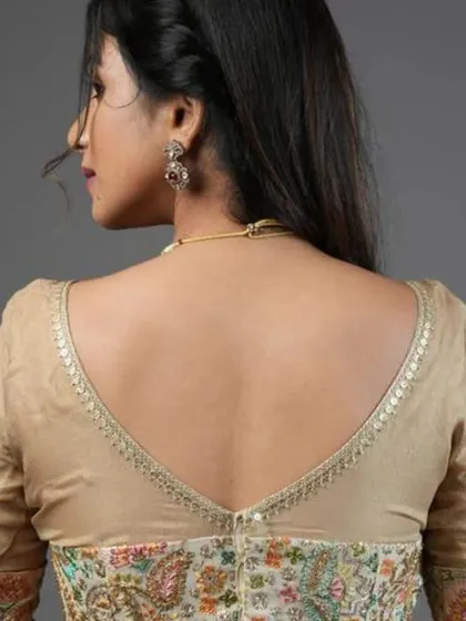 The back view of our cream georgette blouse, featuring a deep V-back and continuous embroidery.