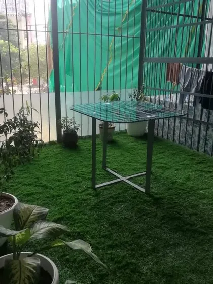 The finished balcony in Gurgaon. The artificial grass provides a perfect green carpet that complements the potted plants and makes the entire space feel more like a garden.