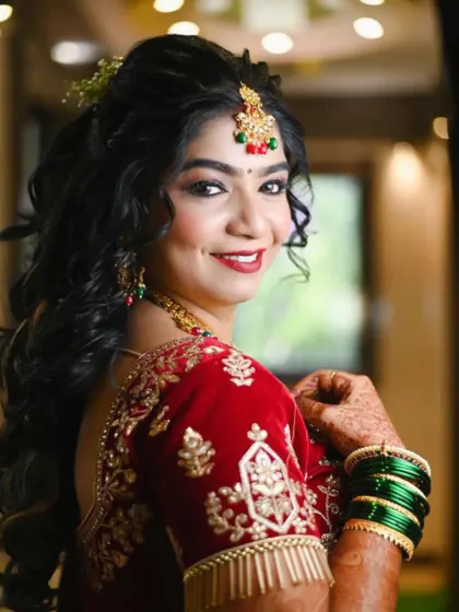 A classic bridal portrait. Her red velvet saree is paired with a bold red lip, soft smoky eyes, and a beautiful half-up hairstyle, creating a timeless and elegant look.