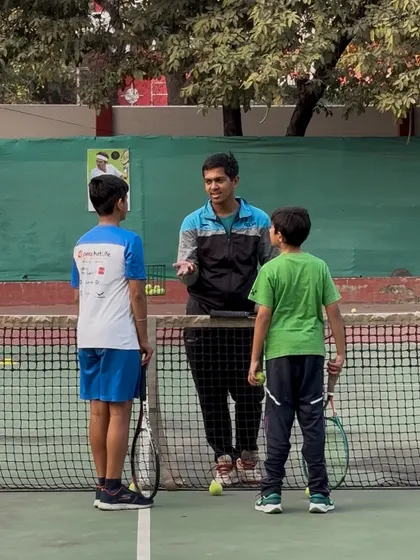 A coach providing tactical advice to two young players by the net. These strategy sessions are just as important as the physical drills.
