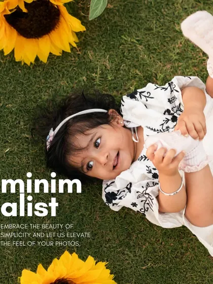 A minimalist outdoor portrait of a baby girl lying on the grass with bright sunflowers. The simple composition and pop of color create a fresh and joyful image.