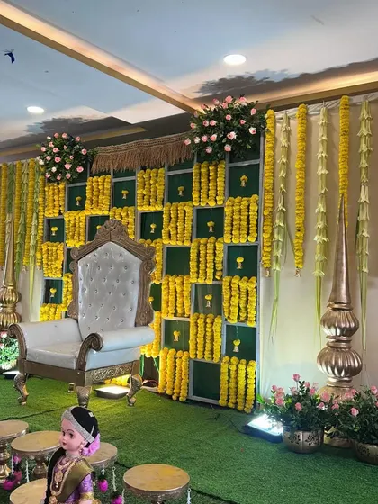 A wider angle of the traditional marigold and green backdrop, showing the full stage with brass lamps and seating arrangements for guests.