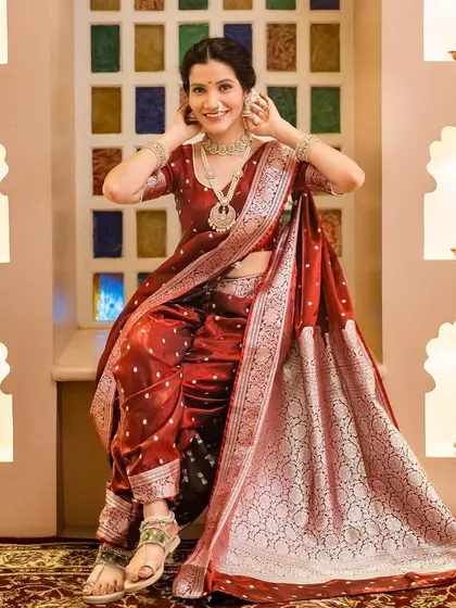 A graceful seated pose in the traditional maroon Navari saree, showcasing the rich fabric and jewelry.
