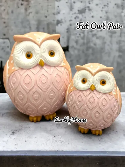 A pair of fat, round owls in a soft pink color. Their cute, chubby design makes them an endearing addition to any room.