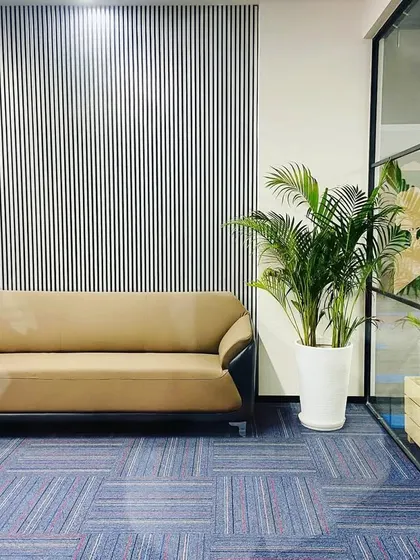 This angle shows how the indoor plants in the foreground connect with the company's green-themed branding visible on the glass wall in the background, creating a cohesive design story.