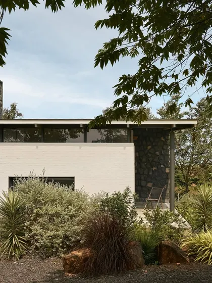 The exterior of Pavilion House, showing how the building is nestled into the landscape, with native plants and grasses growing right up to the structure.