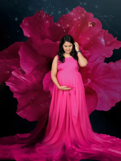Blossoming into motherhood. The mom-to-be is framed by a giant pink flower prop, which beautifully complements her flowing pink gown.