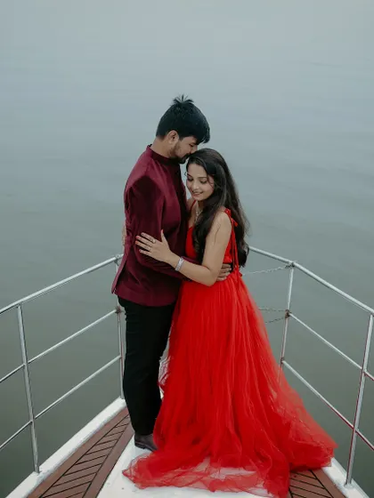 An intimate moment on a yacht. The bright red gown provides a stunning contrast against the water, creating a passionate and romantic pre-wedding photo.