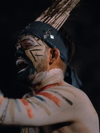 A close-up portrait of a performer with intense tribal face paint, mid-chant. This shot focuses on the raw emotion and cultural detail that makes these performances so powerful.