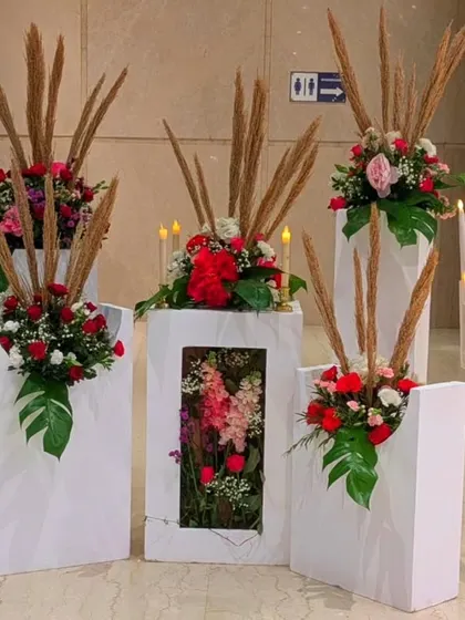 An artistic floral installation on modern white pedestals. I used red roses, pampas grass, and monstera leaves to create these unique arrangements, which can be used to define a space or as standalone decor pieces.
