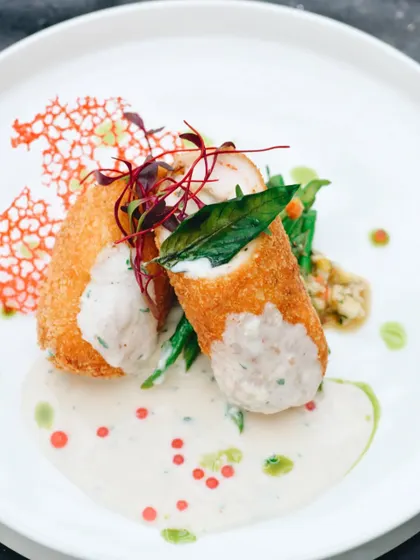 This beautifully plated dish is all about fine dining. The bright, clean lighting and careful composition highlight the chef's artistry, from the crispy texture of the roll to the delicate sauce work.